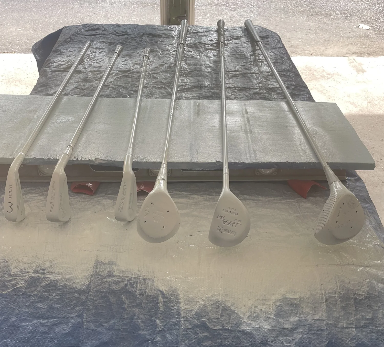 Primed golf clubs laid out before painting